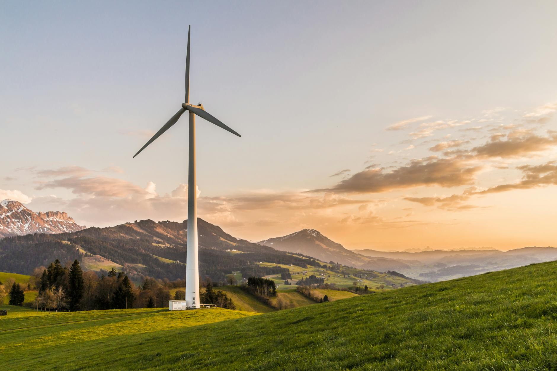 white wind turbine in front of mountains and foothills